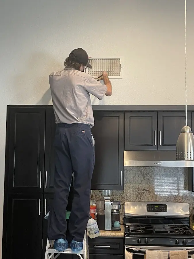 Technician inspecting an air vent during HVAC service in Welby